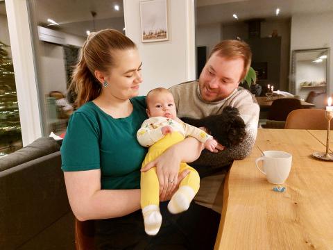 vanhemmat ja pieni lapsi kotona keittiönpöydän ääressä